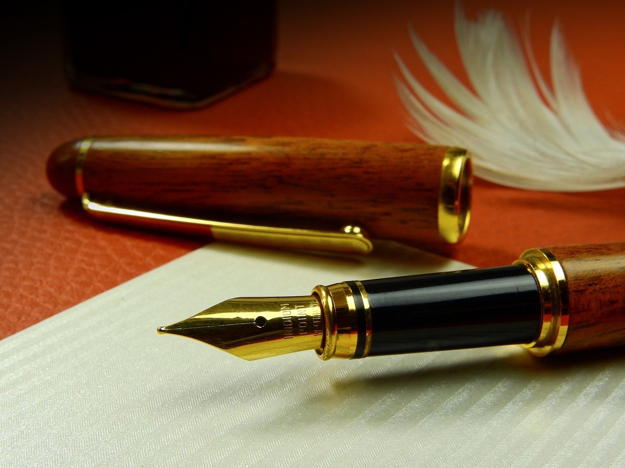 Una pluma fuente y una pluma de ave sobre una mesa.
